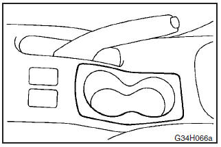 The cup holder is located at the side of the parking brake lever.